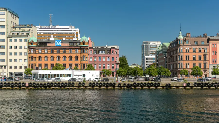 Centrum Malmö nad kanałem: kamienice z przełomu wieków za nadbrzeżną ulicą, przed nimi basen portowy.